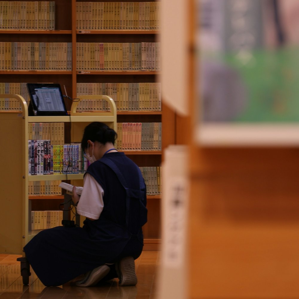 図書館の書架で本を選ぶ人
